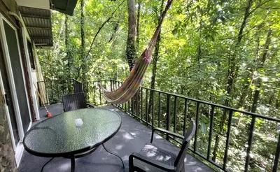 a hammock on a balcony with a table and chairs at Nature Lovers Quepos in Quepos