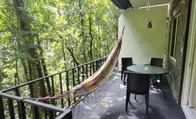 a hammock on a balcony with a table and chairs at Nature Lovers Quepos in Quepos