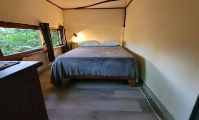 a bedroom with a bed in a room with a window at Nature Lovers Quepos in Quepos