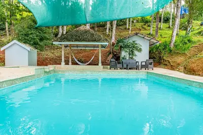 a swimming pool with two chairs and a gazebo at Colinas Tinamastes in San Isidro