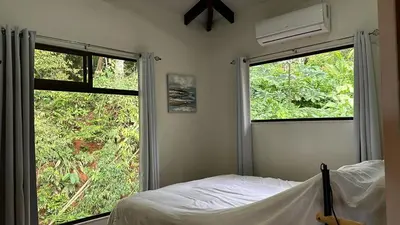 a bedroom with a bed and two large windows at Colinas Tinamastes in San Isidro