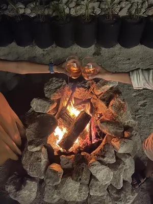 two people holding wine glasses over a fire at SurFreak Backyard Glamping CoWorking Experience in Mal País