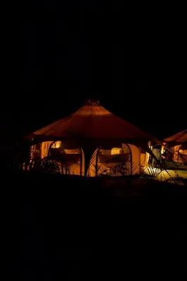 a group of tables and chairs under umbrellas at night at SurFreak Backyard Glamping CoWorking Experience in Mal País