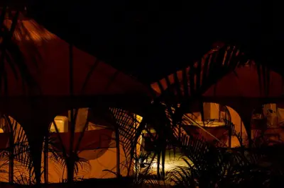 a group of umbrellas are lit up at night at SurFreak Backyard Glamping CoWorking Experience in Mal País