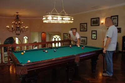 two men playing pool in a living room at El Castillo de Esparza in Esparza