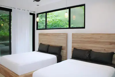 two beds in a room with two windows at Nosara Verde in Nicoya