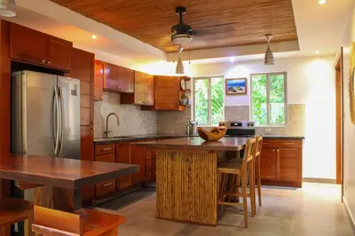 a kitchen with wooden cabinets and a stainless steel refrigerator at Nosara Verde in Nicoya