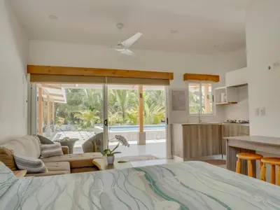 a bedroom with a large bed and a living room at Casa Las Olas in Esterillos