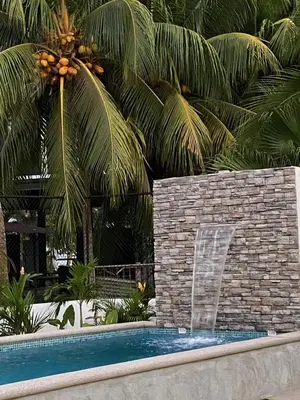a swimming pool with a fountain in a resort at Casa Las Olas in Esterillos
