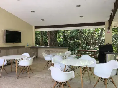 a room with tables and white chairs and a tv at Brisa del Río Santa Ana in Río Oro