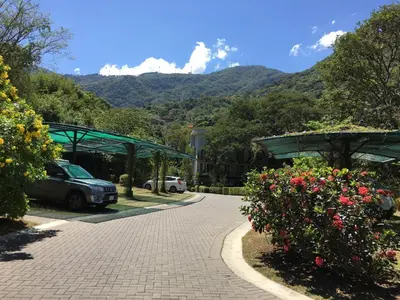 a parking lot with cars and flowers with mountains in the background at Brisa del Río Santa Ana in Río Oro