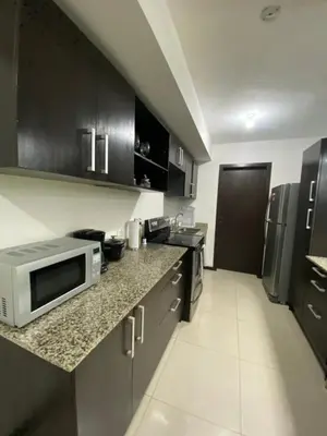 a kitchen with black cabinets and a microwave at Brisa del Río Santa Ana in Río Oro