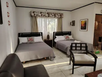 a bedroom with two beds and a chair at Villa jr 1 Private Jacuzzi near peñon guacalillo in Tivives