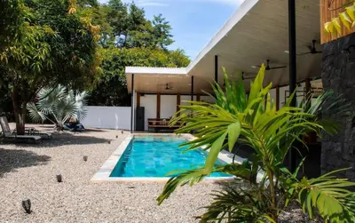 a swimming pool in front of a house at Oshy Sunset Apartments - 10 mins from Tamarindo in Villarreal