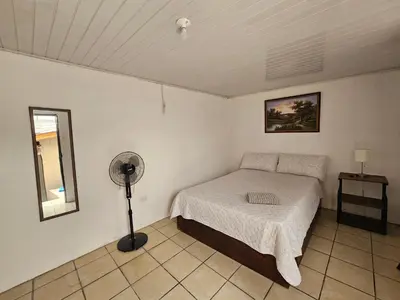 a small bedroom with a bed and a fan at La casa de Eu in Atenas