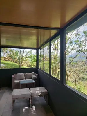 a screened in porch with a couch and windows at Arenal volcano apartment with panoramic view in El Castillo de La Fortuna