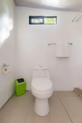 a bathroom with a white toilet and a green trash can at Pozas y Cascadas La Presa Habitación 3 in Río Cuarto