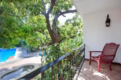 a porch with a bench and a tree and a swimming pool at Hotel Boyeros in Liberia