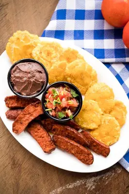 a plate of breakfast food with eggs sausage and dips at Hotel Boyeros in Liberia