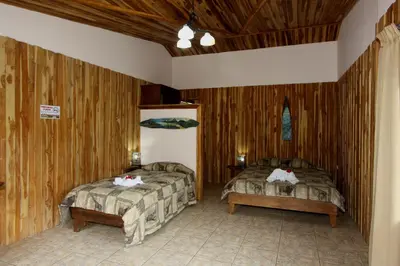 two beds in a room with wooden walls at Historias Lodge in Monteverde Costa Rica