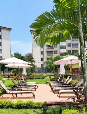a bunch of lounge chairs with umbrellas in a park at Jaco Beach Condos in Jacó
