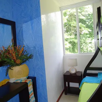 a room with a blue wall with a vase of flowers at Jaco Beach Condos in Jacó
