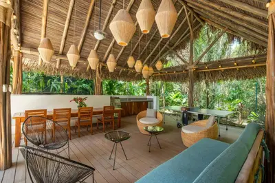 a patio with a blue couch and chairs and tables at Green House 1 in Nosara