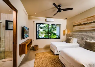 a bedroom with two beds and a ceiling fan at Xanadu Luxury Villa 5BR - 10P Tamarindo - Hacienda Pinilla in Tamarindo