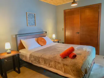 a bedroom with a bed with orange pillows on it at Casitas la Esquina in Monteverde Costa Rica