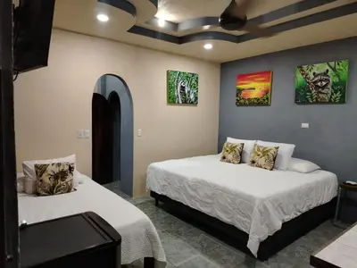 a bedroom with two beds and paintings on the walls at Casa veranera in Quepos