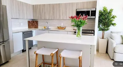 a kitchen with a white island with two stools at Beachfront Condo Stunning Views in Jacó