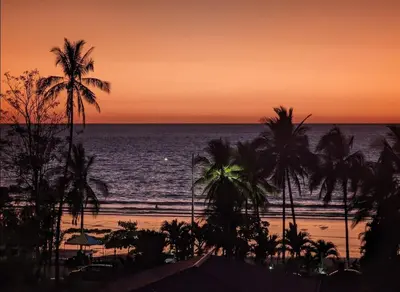 a sunset over a beach with palm trees and the ocean at Beachfront Condo Stunning Views in Jacó