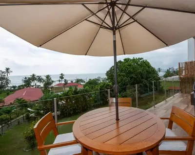 a wooden table with an umbrella on a balcony at Beachfront Condo Stunning Views in Jacó
