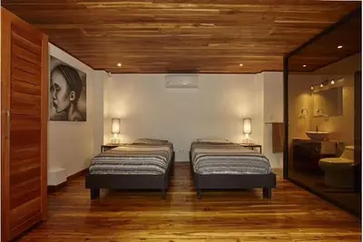 two twin beds in a room with a bathroom at Casa Canopy in Nosara