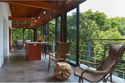 a screened in porch with chairs and a table at Casa Canopy in Nosara