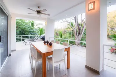 a dining room with a table and chairs and a balcony at Casa Coastin in Nosara