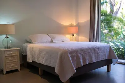 a bed in a bedroom with two lamps and a window at Casa Coastin in Nosara