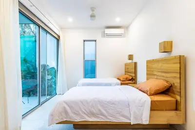 two beds in a bedroom with a large window at Green house 1&2 Green Complex in Nosara