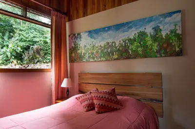 a bedroom with a bed with a large painting on the wall at Cala Lodge in Monteverde Costa Rica