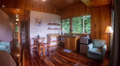 a living room with a kitchen and a table and chairs at Cala Lodge in Monteverde Costa Rica