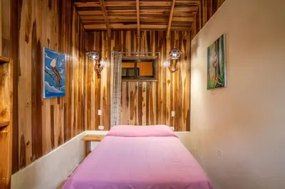 a bedroom with a pink bed in a wooden wall at Monteverde Villa Lodge in Monteverde Costa Rica