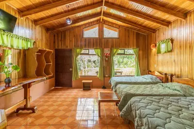 a bedroom with three beds in a room with wooden walls at Monteverde Villa Lodge in Monteverde Costa Rica