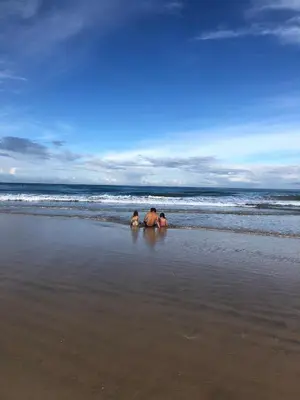 three people sitting in the water on the beach at Casa Del Oeste, Playa Avellanas Beach House in Playa Avellana