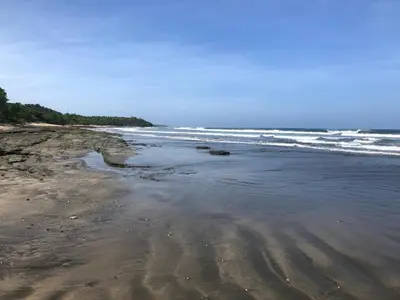 a sandy beach with waves in the ocean at Casa Del Oeste, Playa Avellanas Beach House in Playa Avellana
