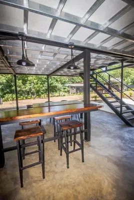 a table with two stools and a table and benches at Casa Del Oeste, Playa Avellanas Beach House in Playa Avellana