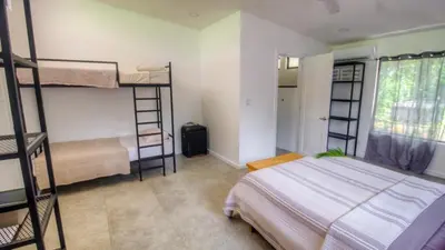 a bedroom with bunk beds and a bed and a window at Casa Del Oeste, Playa Avellanas Beach House in Playa Avellana