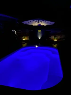 a blue swimming pool with an umbrella in the dark at Alojamiento con piscina in Aguas Zarcas