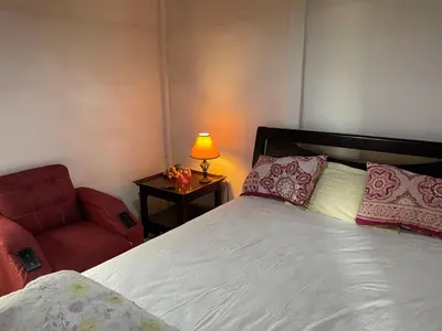 a bedroom with a bed and a red chair at Casita Campos in Sarapiquí