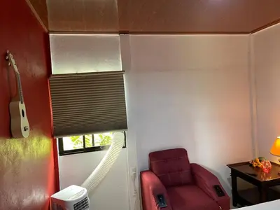 a bedroom with a red chair in a room with a guitar at Casita Campos in Sarapiquí