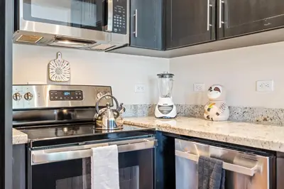 a kitchen with stainless steel appliances and black cabinets at Suite 2 Howler - Beach & Pool Condo with 2 BR in Brasilito